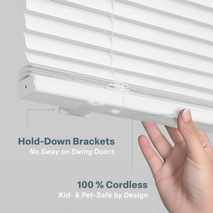 A close-up image showing a hand lifting the bottom rail of white horizontal blinds to demonstrate two key features: Hold-Down Brackets, which prevent swaying on swing doors, and a 100% Cordless design that is kid- and pet-safe. The clean, minimalist visual uses thin pointer lines to highlight the brackets and the cordless mechanism against a light gray background.