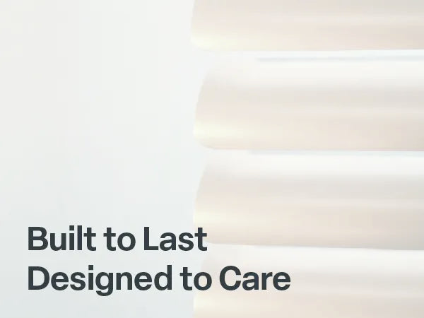 Close-up view of durable white blind slats with the bold text "Built to Last, Designed to Care" in the bottom left corner.